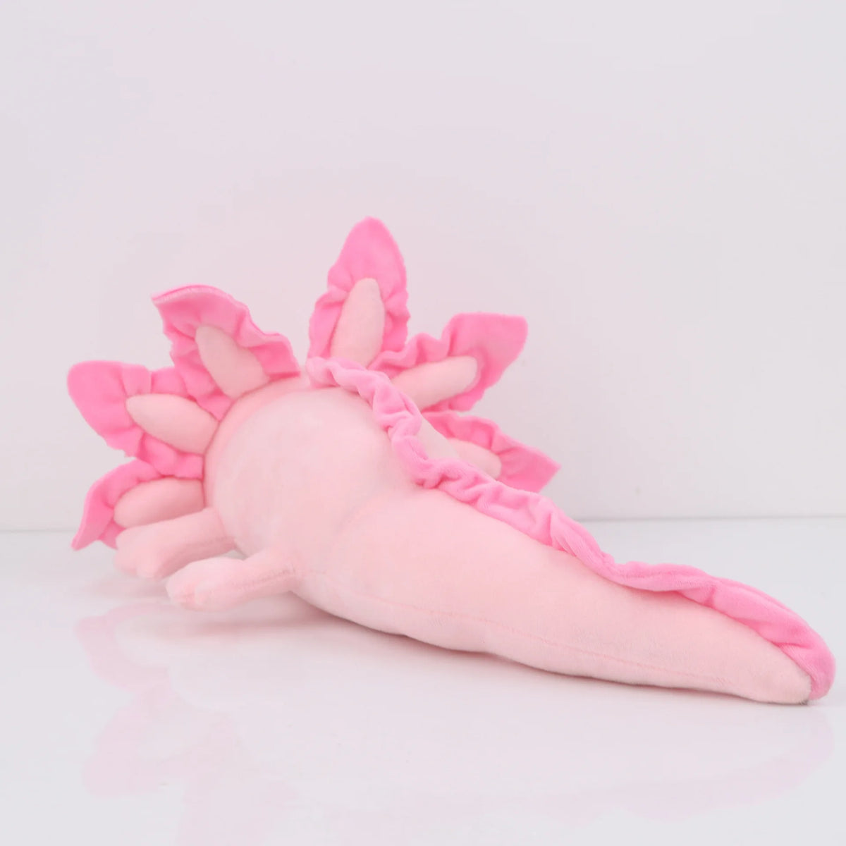 Peluche axolotl rose, format qui se remarque sur un lit