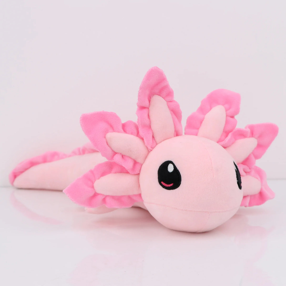 Peluche axolotl rose de 45 cm, posée sur une tête de lit