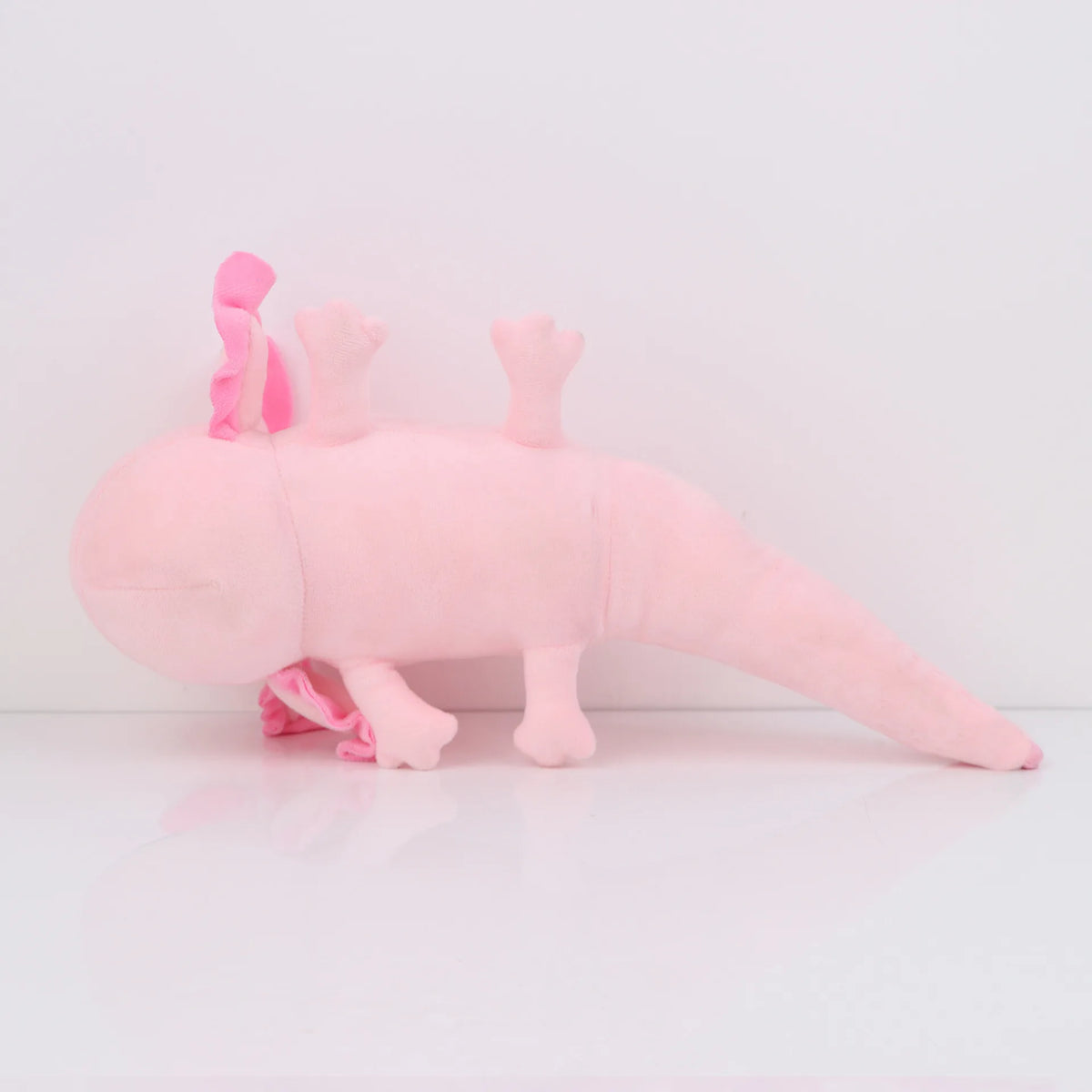 Peluche axolotl rose, corps allongé et pattes courtes bien visibles